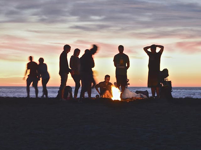 Young adults by fire on beach